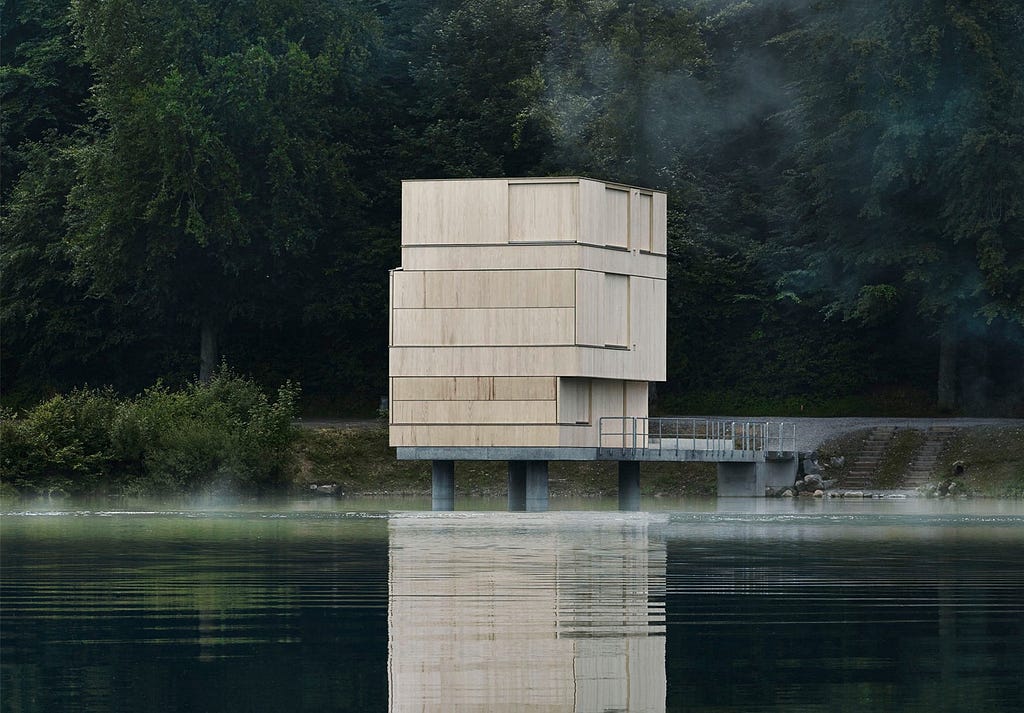 A wooden, blocky structure sitting on the edge of a lake.