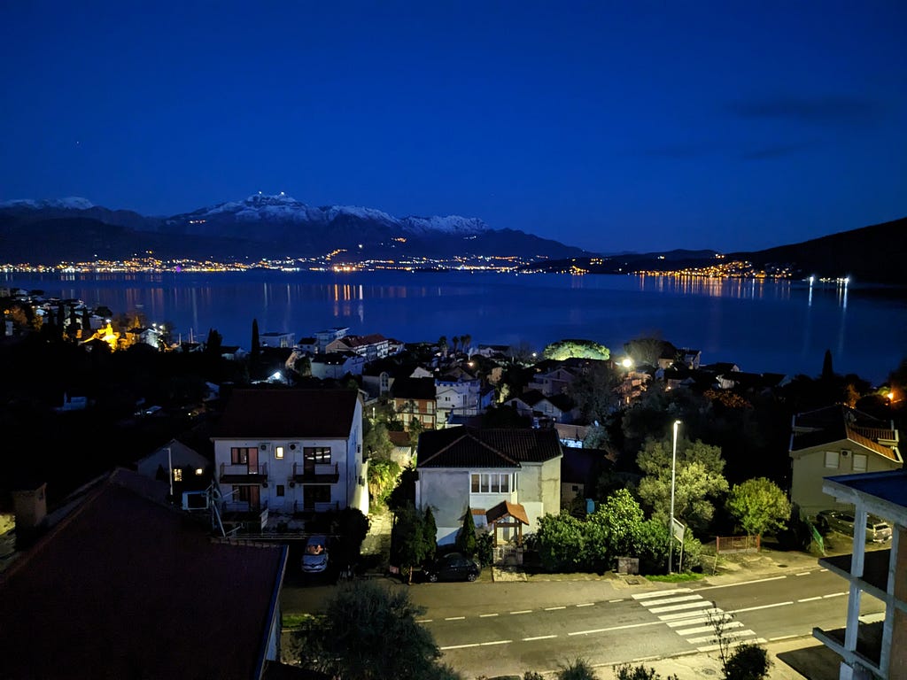 A view of the bay from our balcony at night: the twinkling lights of many small establishments around the bay glitter on the evening water.