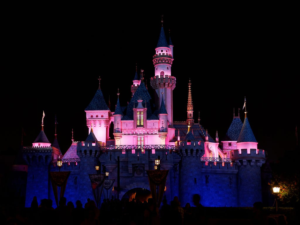 Sleeping Beauty Castle illuminated in pink light at night