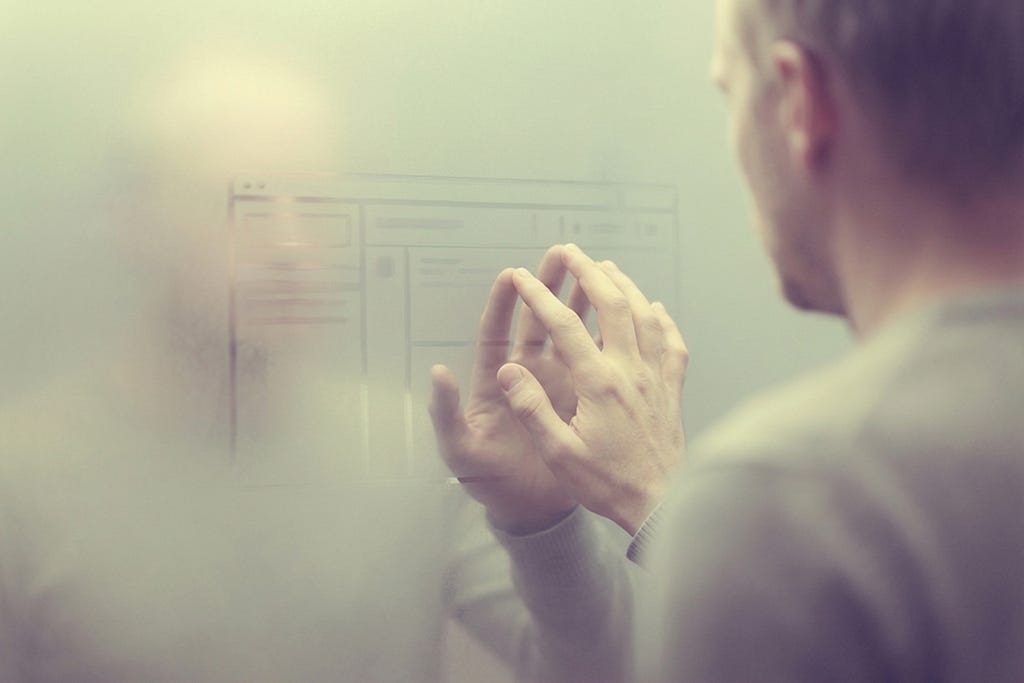 A person with hands in reflective pose, with a blurred screen or interface visible in the background, depicting conscious work and agency.