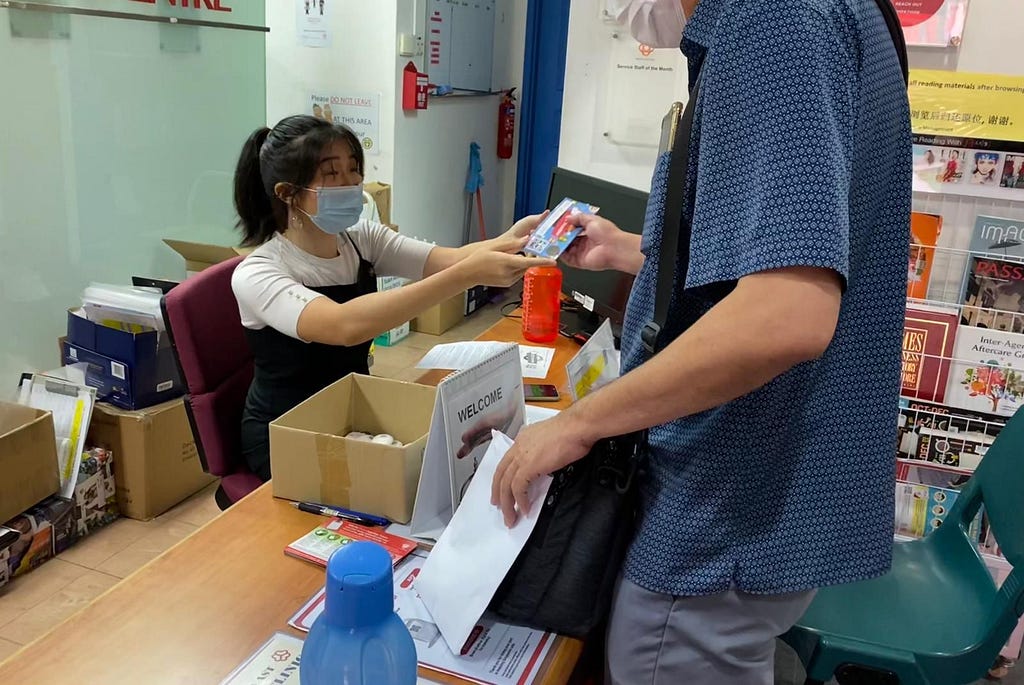 A resident collecting paper vouchers from CC staff