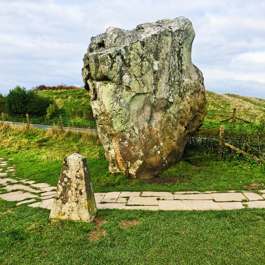 Large ancient stone with a paved footpath in front of it
