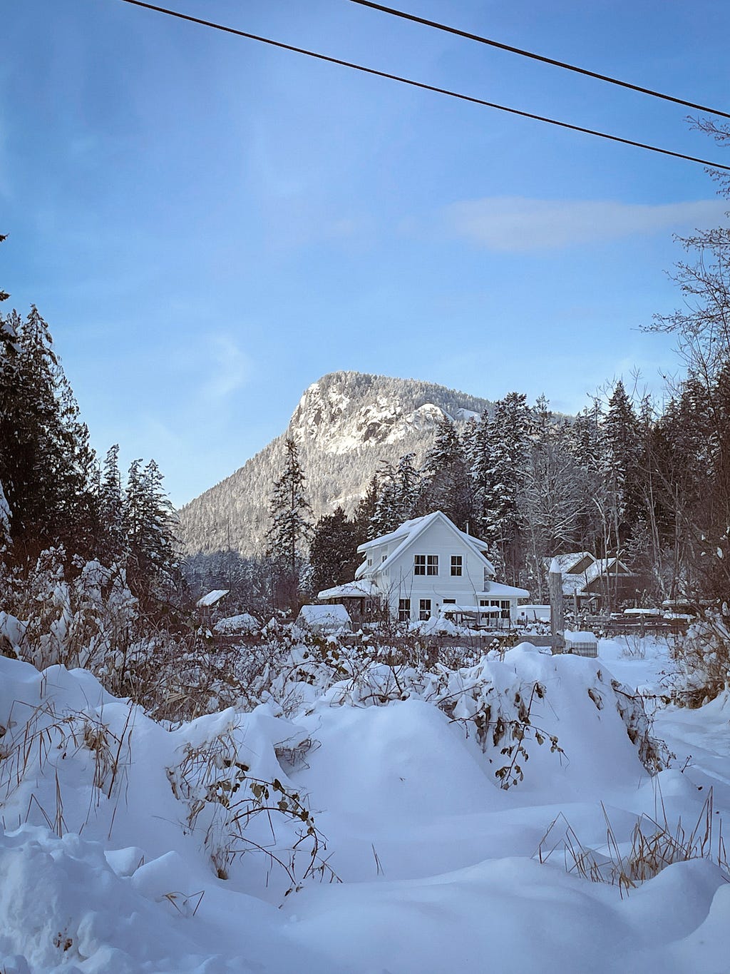 A scenic winter view of a rural house with a snow covered mountain in the background
