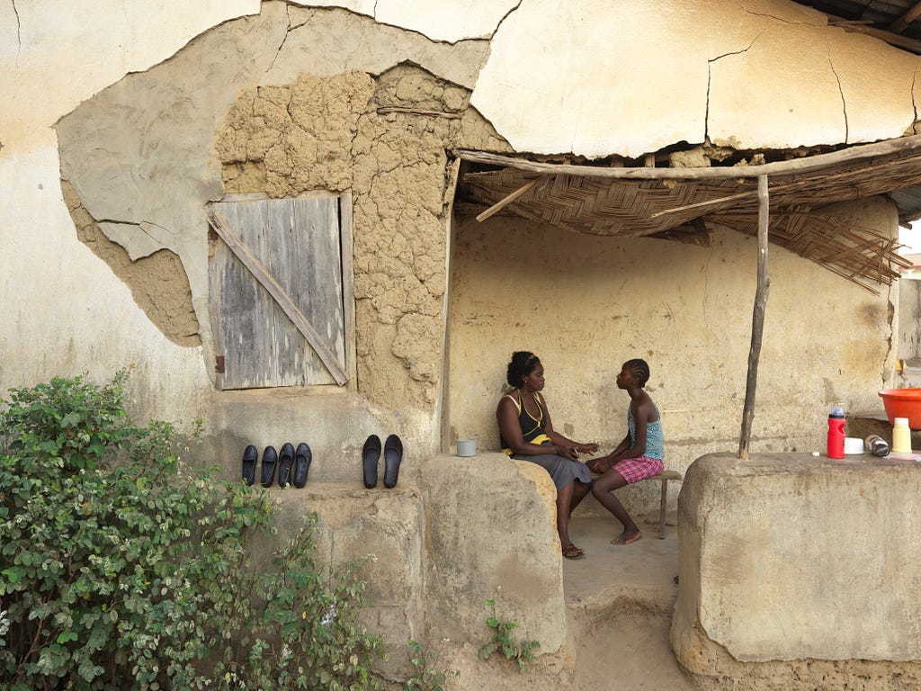 Two women in Sierra Leone discuss contraception on their patio.