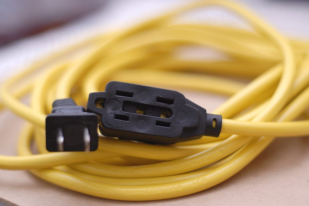 a yellow extension cord with 2-pin black plugs