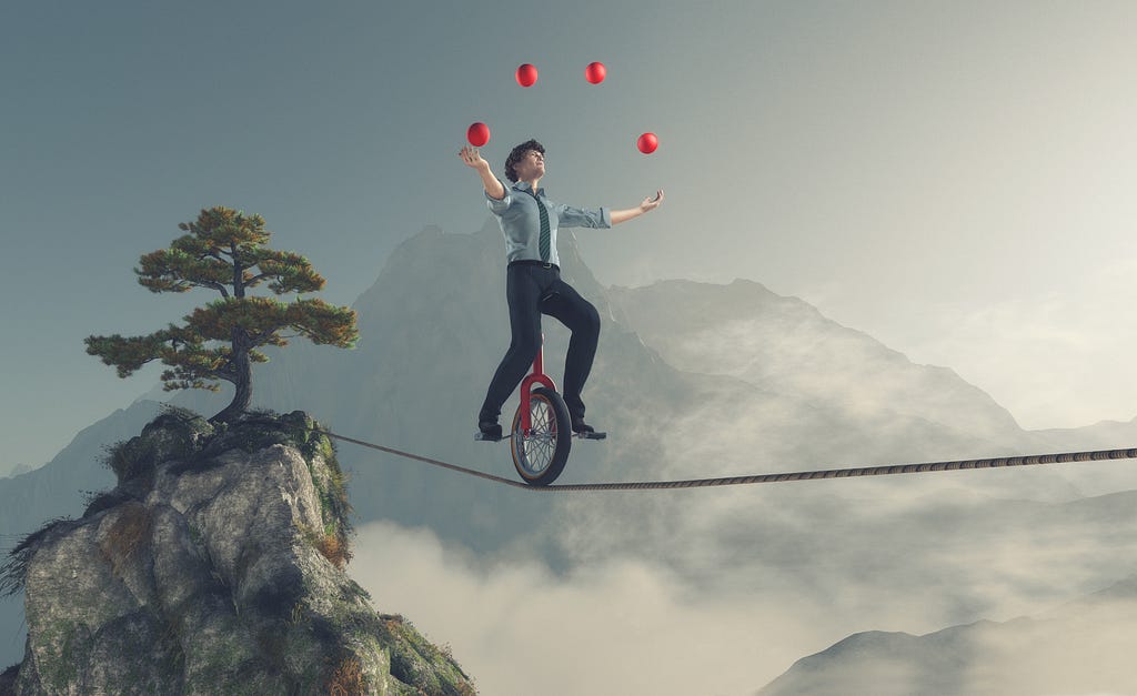 Pessoa andando em um monociclo em cima de uma corda bamba enquanto faz malabarismos com 4 bolas, simbolizando o desafio que é fazer várias coisas ao mesmo tempo