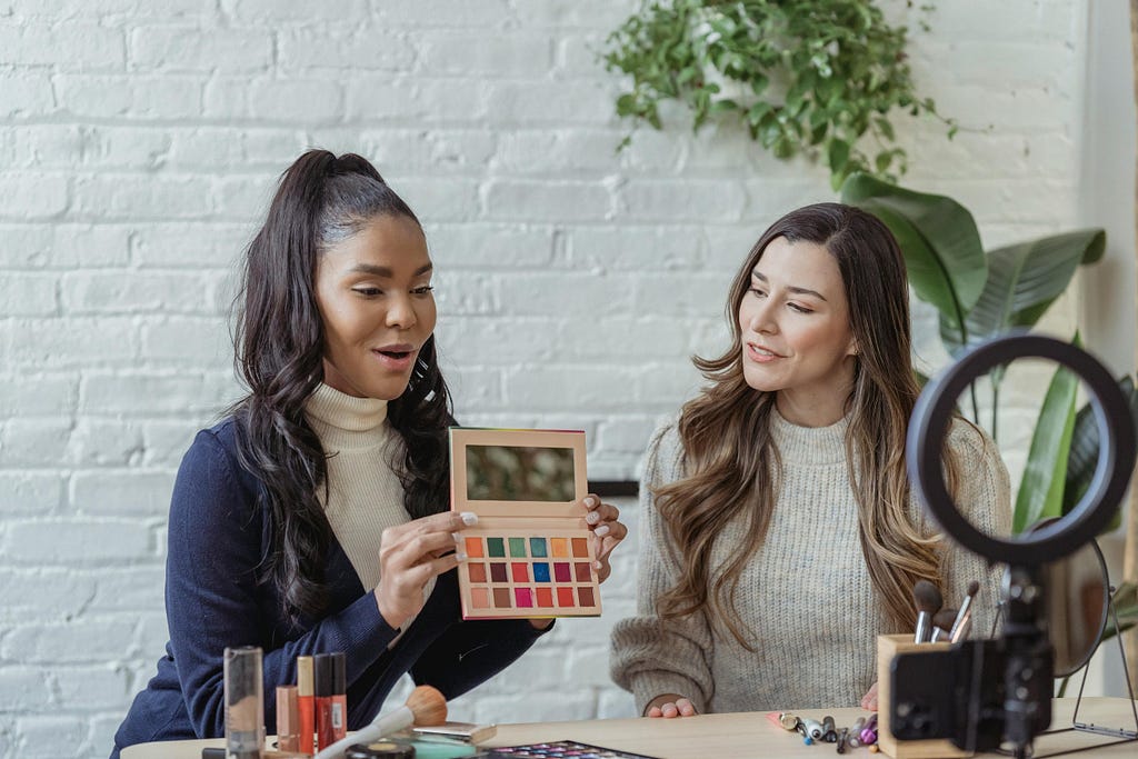 Make-up influencer working to create content for a brand. She is holding up an eye-shadow pallete
