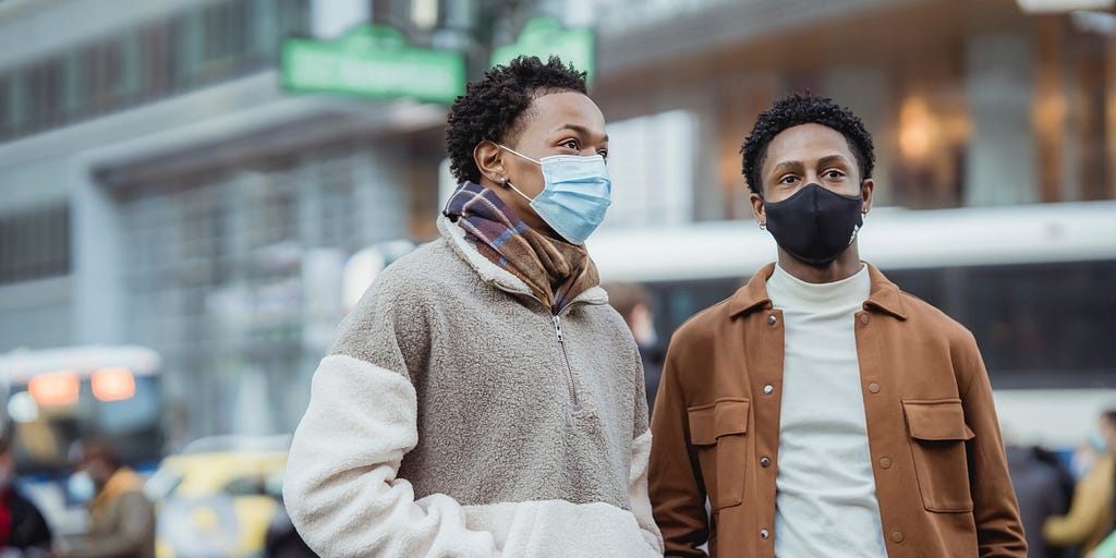 Two men in the city wearing face masks