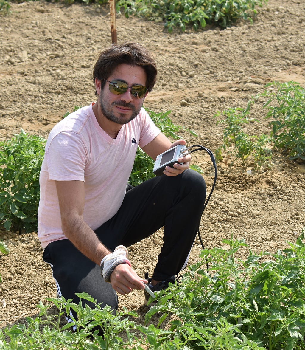 Santiago Freyria measures crop health in a field.