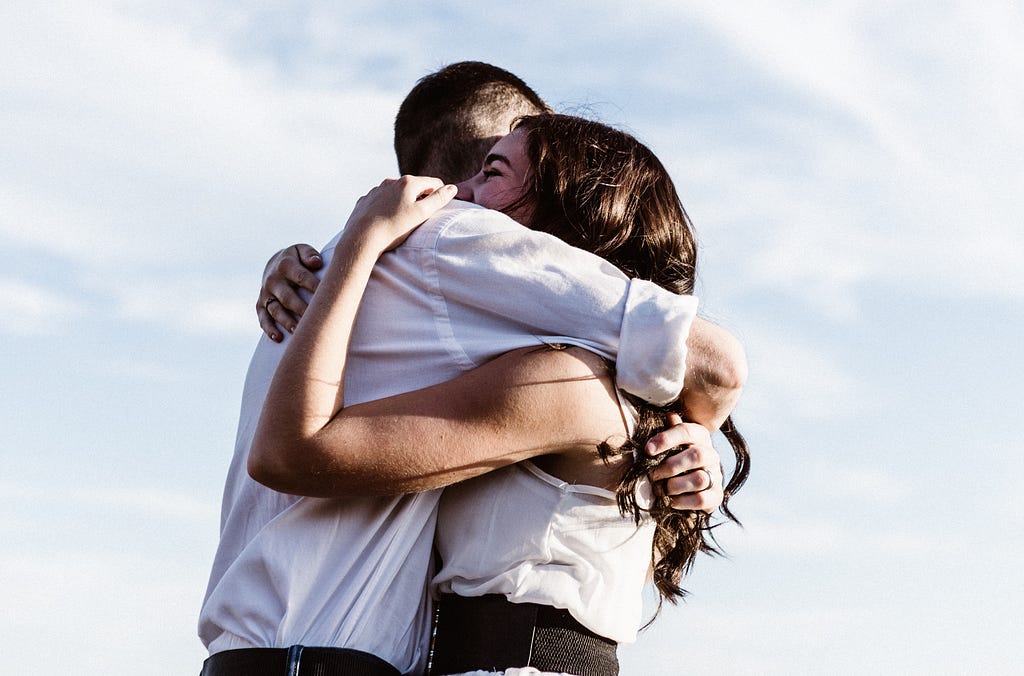 A young man and woman hug each other