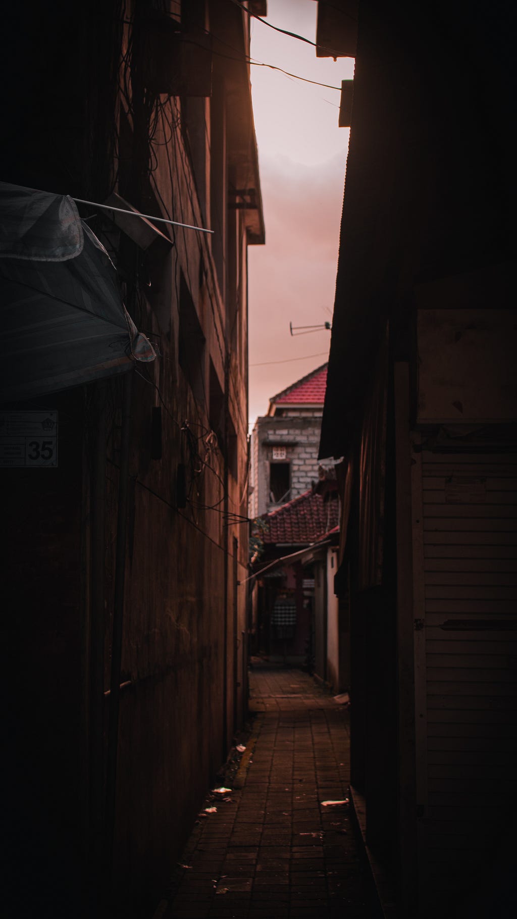 An alley beneath a pink-orange evening sky.