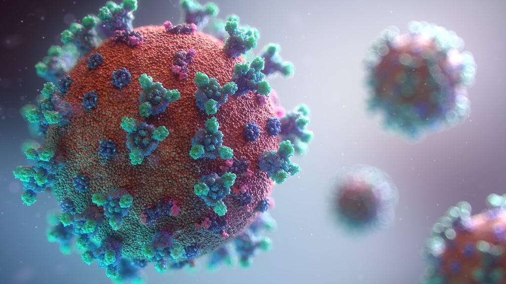 A picture of particles of the Covid 19 virus. The particles are red balls with green and blue spikes on their surface.