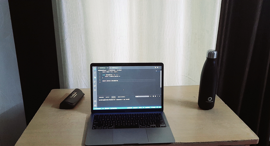 Desk with a laptop computer, glasses case, and water bottle