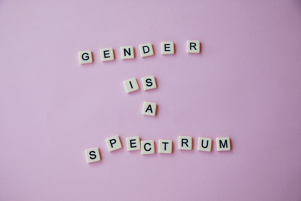 Inscription Gender is a spectrum made of scrabble letters against pink background