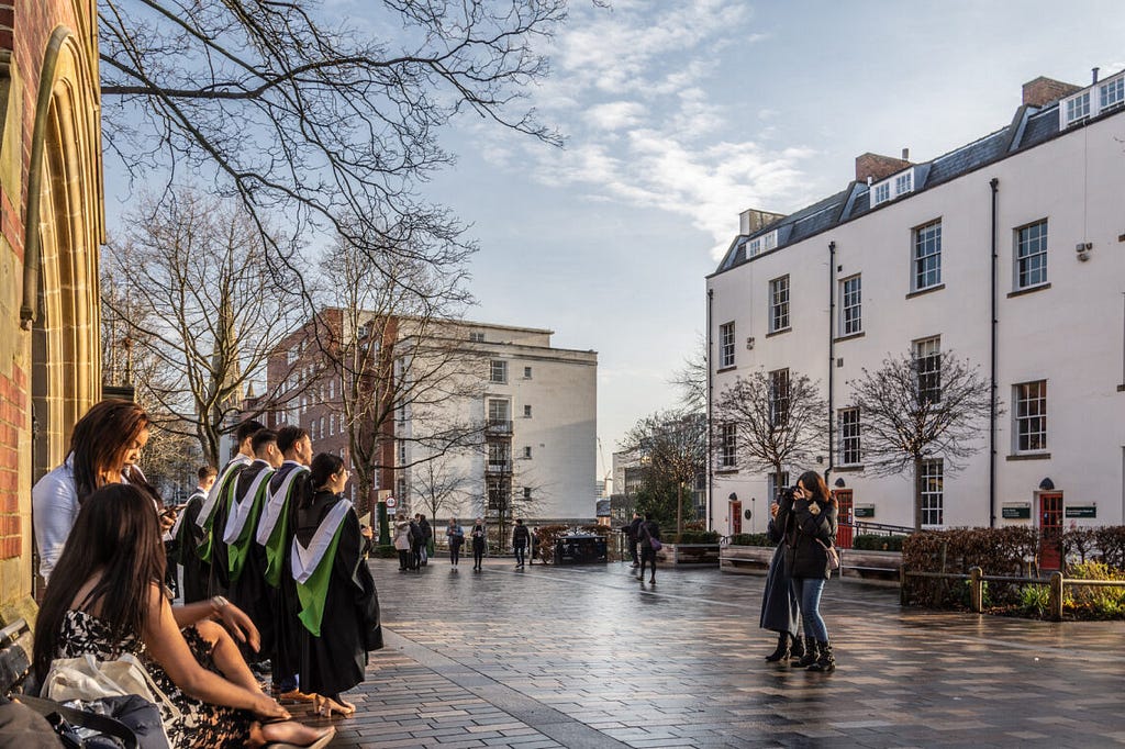 A group of students in graduation gowns getting their photo taken outside the Great Hall.