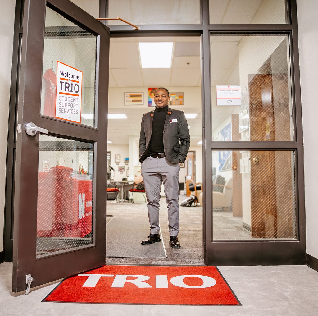 Cameron smiles for a photo at the entrance of the TRIO office