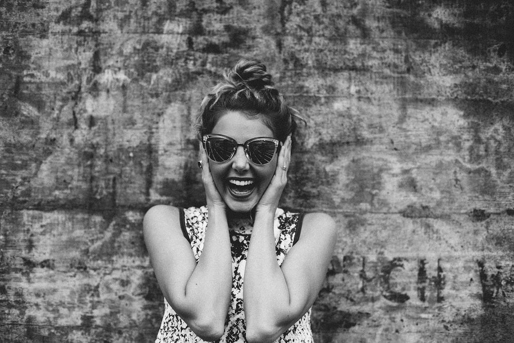 The picture is in black and white of a women very excited cupping her face with her hands