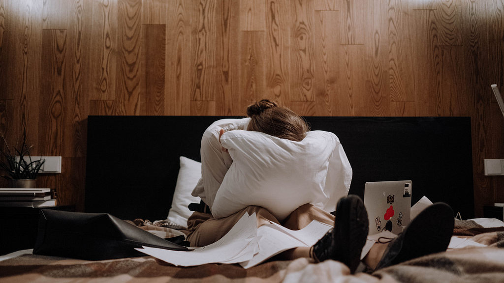 woman crying on a bed surrounded by paper