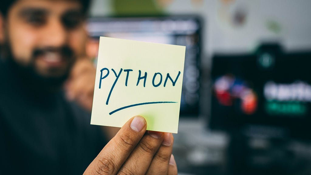 Someone holding a sticky note with “Python” written on it
