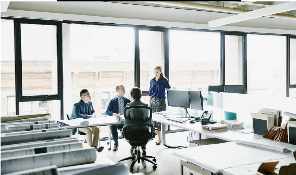 4 disheartened employees in an empty office space.