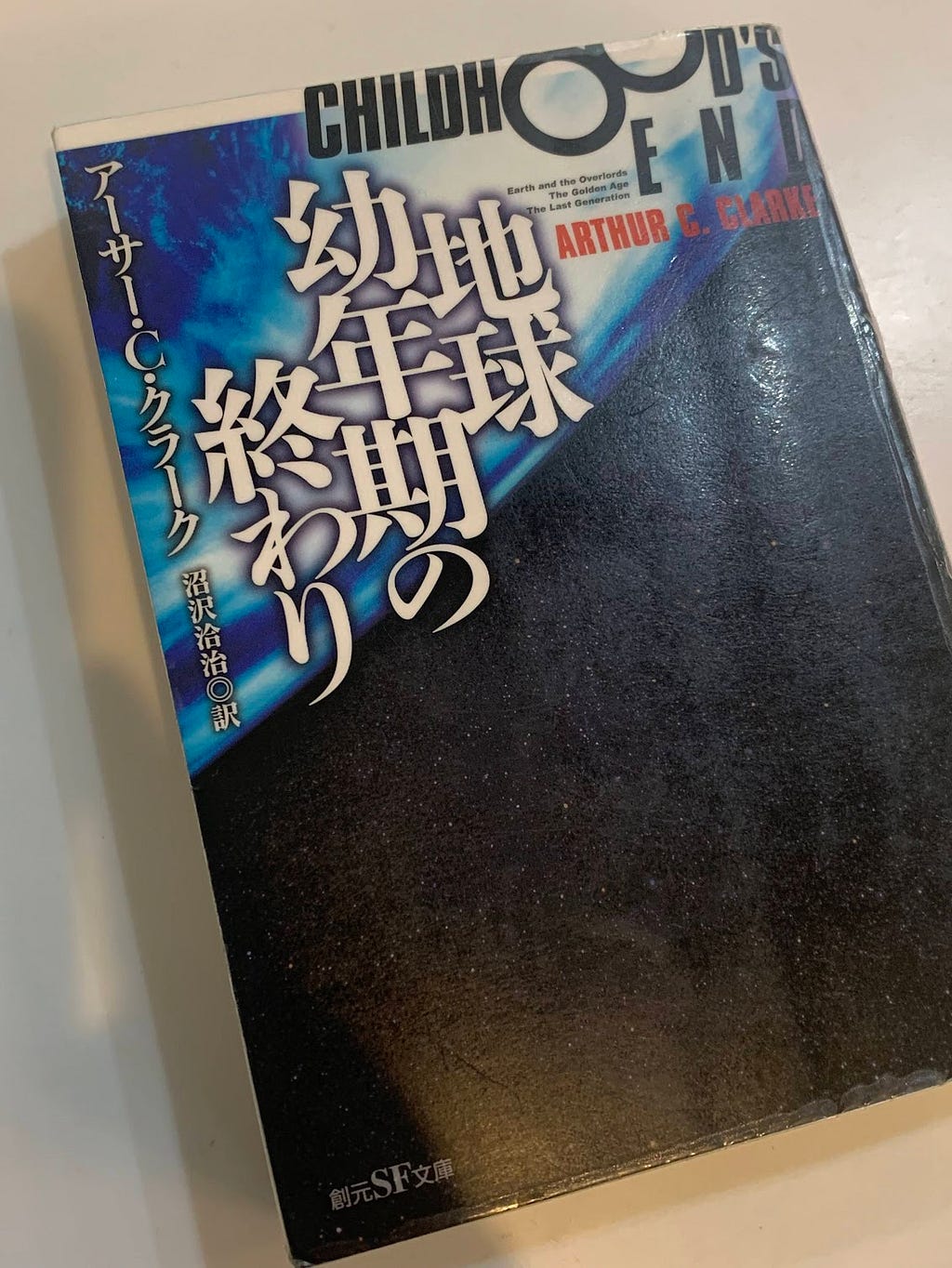 A photo of the Japanese edition of ‘Childhood’s End’ by Arthur C. Clarke. The cover features a dark, cosmic background with bold white and blue text.