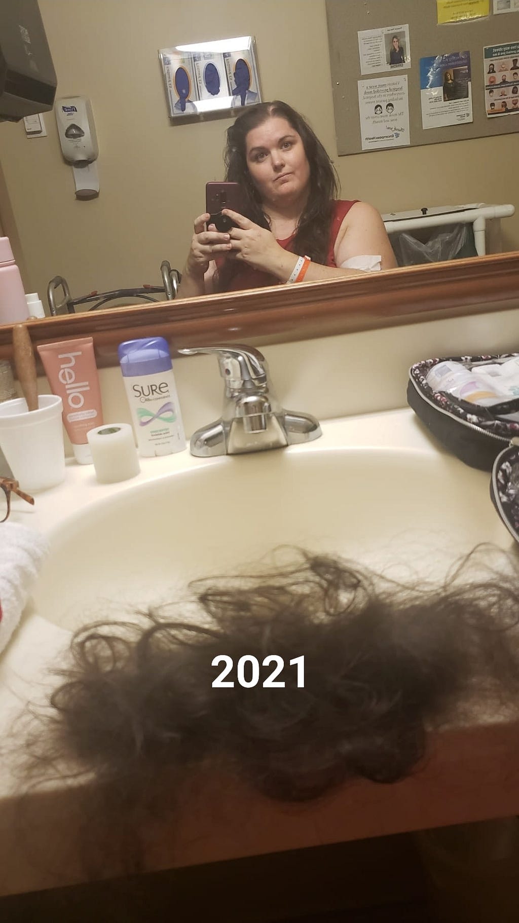 Photo of the author, Jessica Reed, taking a mirror selfie. A pile of hair is visible in the foreground of the photo, and Jessica’s hair on her head is thinned. The year “2021” is written on the photo.