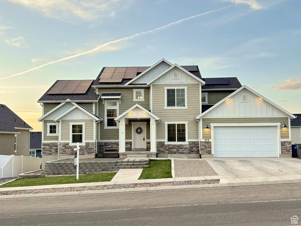 Modern two-story home with solar panels in Elk Ridge, Utah, showcasing sustainable energy under a partly cloudy sky.