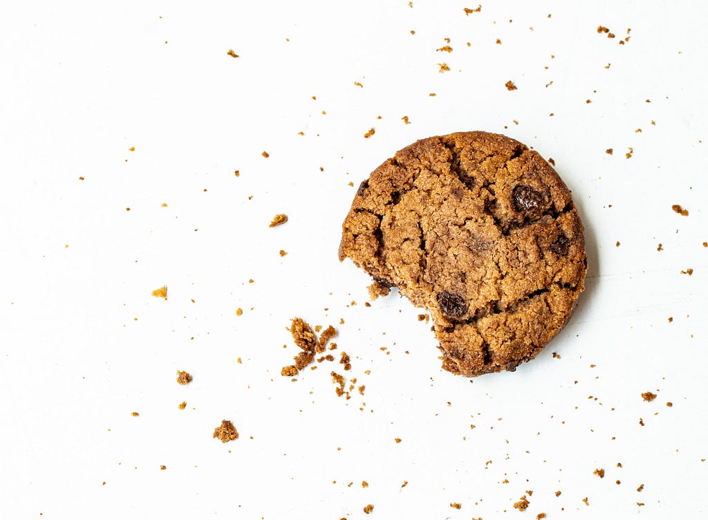 A biscuit that has already been bitten off and some crumbs around it.