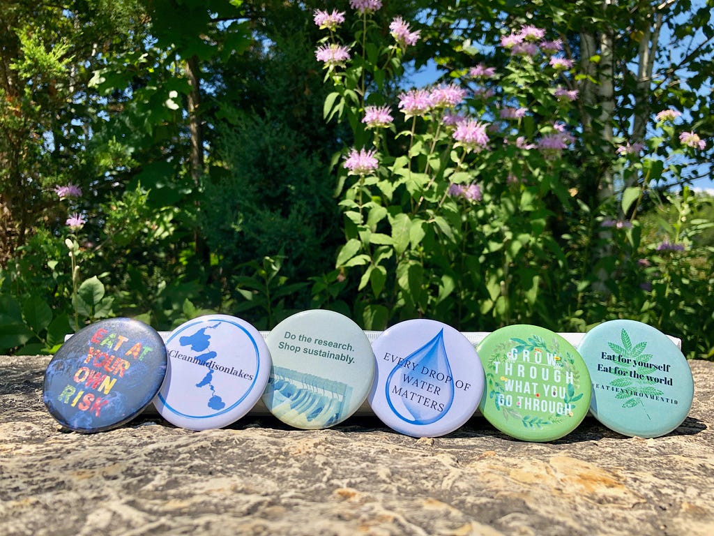 Six buttons designed by writers to support their causes, lined up in the garden.