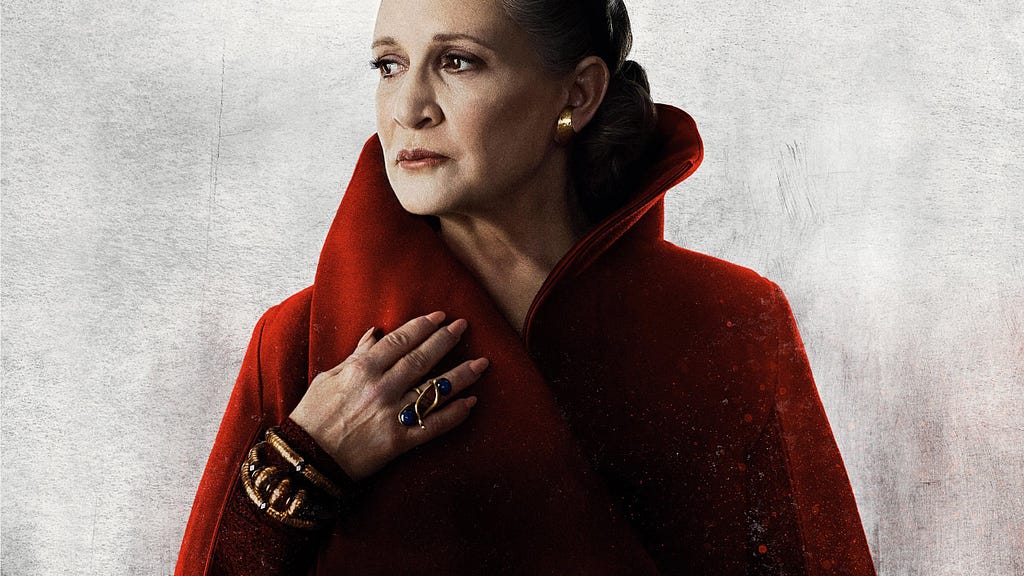 Image description: General Leia Organa looking off to the right and looking regal in a high-collared red cape. End ID