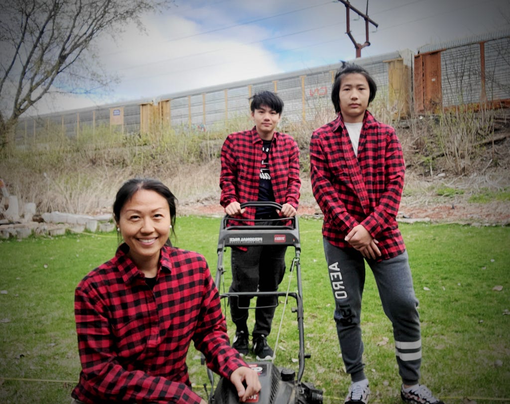 mom and sons in red flannel shirts posing for picture with lawn mower lawnup