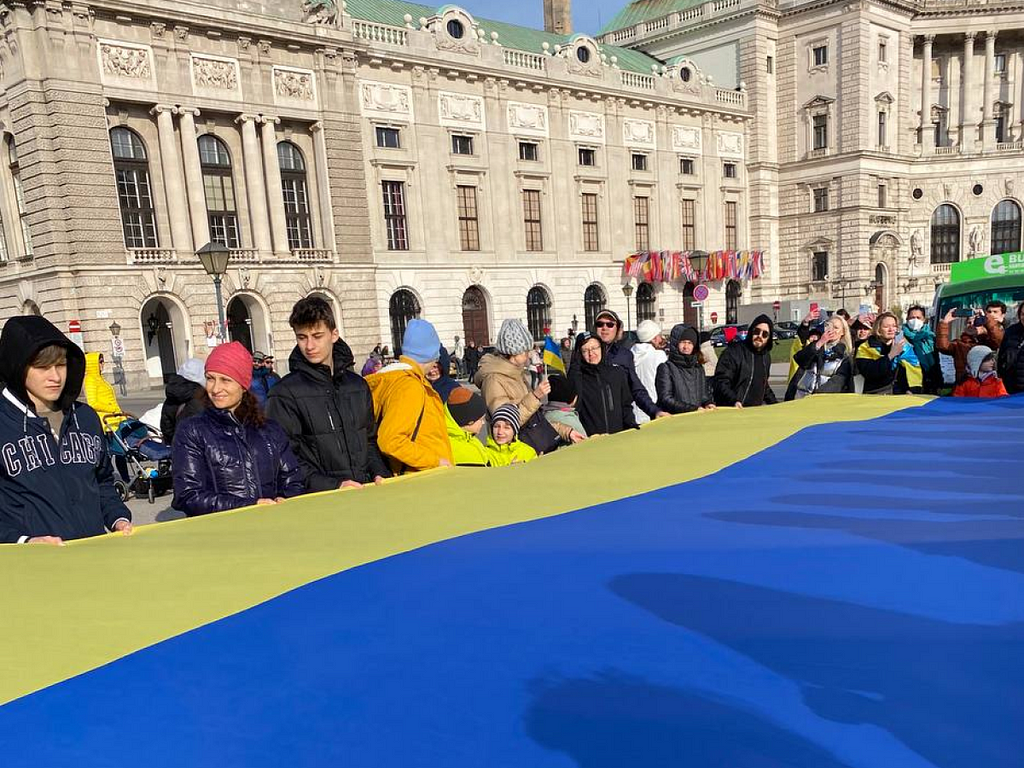 People holding a big yellow and blue Ukrainian flag in Vienna to support Ukrainians in 2022 during the Russian aggression