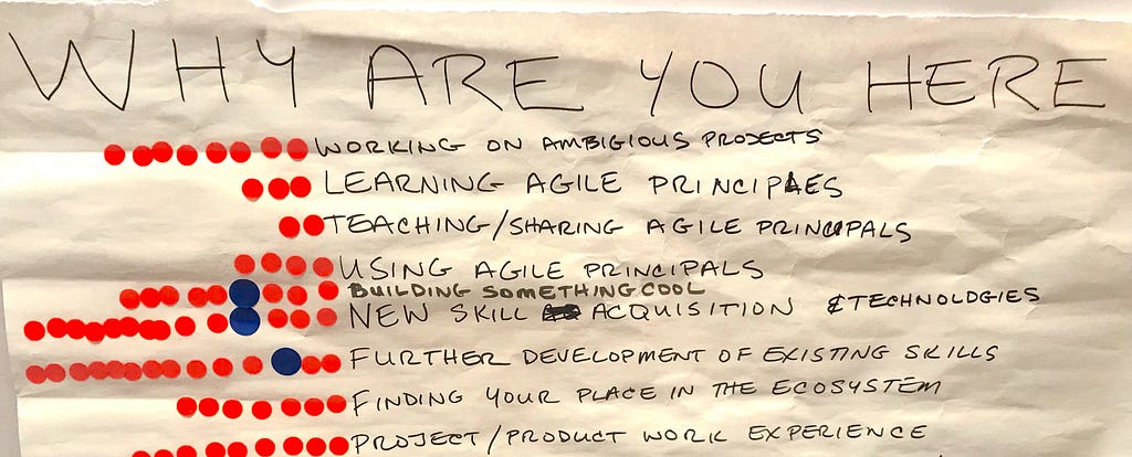 Photo of a big piece of paper used in a workshop. Title is “Why are you here?” Participants’ answers are listed.