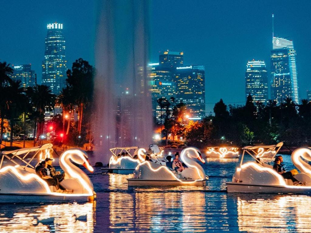 Echo Park lake at night with lit up swan boats and DTLA skyline in the moonlit blue background in Los Angeles, CA.