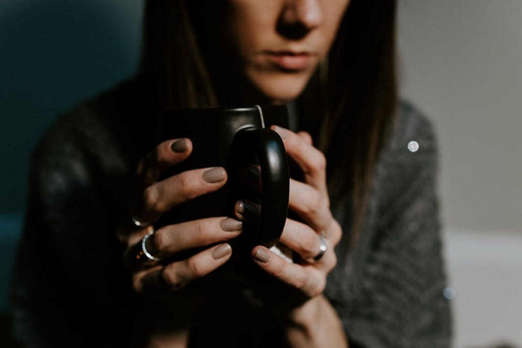 Kelly Sikkema took this photo of a woman in a gray shawl holding a black tea mug.
