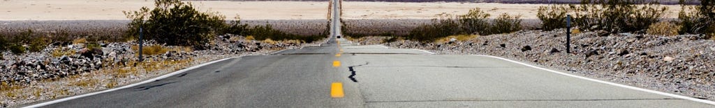 A straight stretch of desert highway meets the horizon