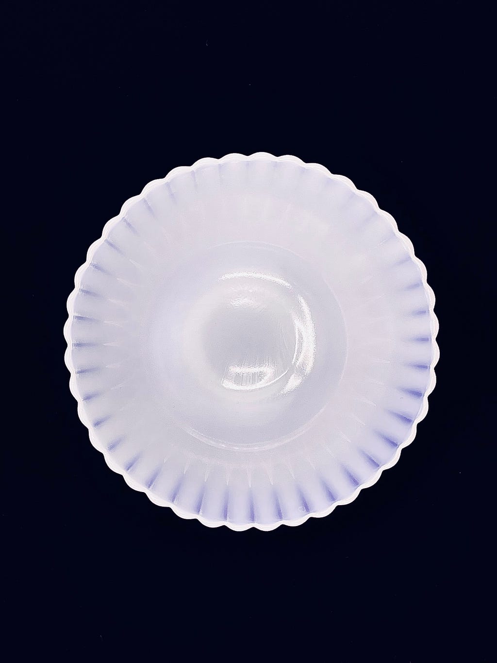 A top-down view of the Monax Petalware compote dish, into its opaque white well against a black backdrop.