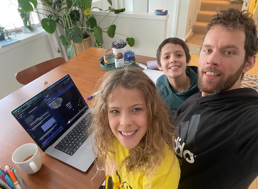 Me and my kids sitting in front of a laptop with pajamas and messy hair.