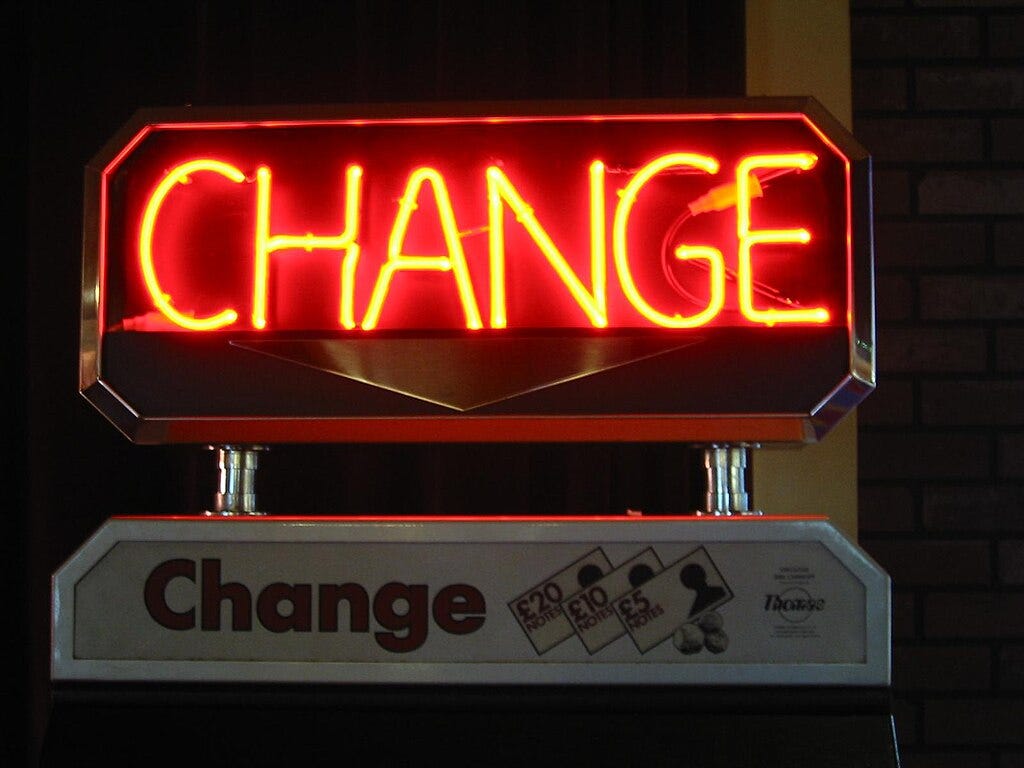 CHANGE in neon signage above a Change sign with money icons, likely some kind of change making machine