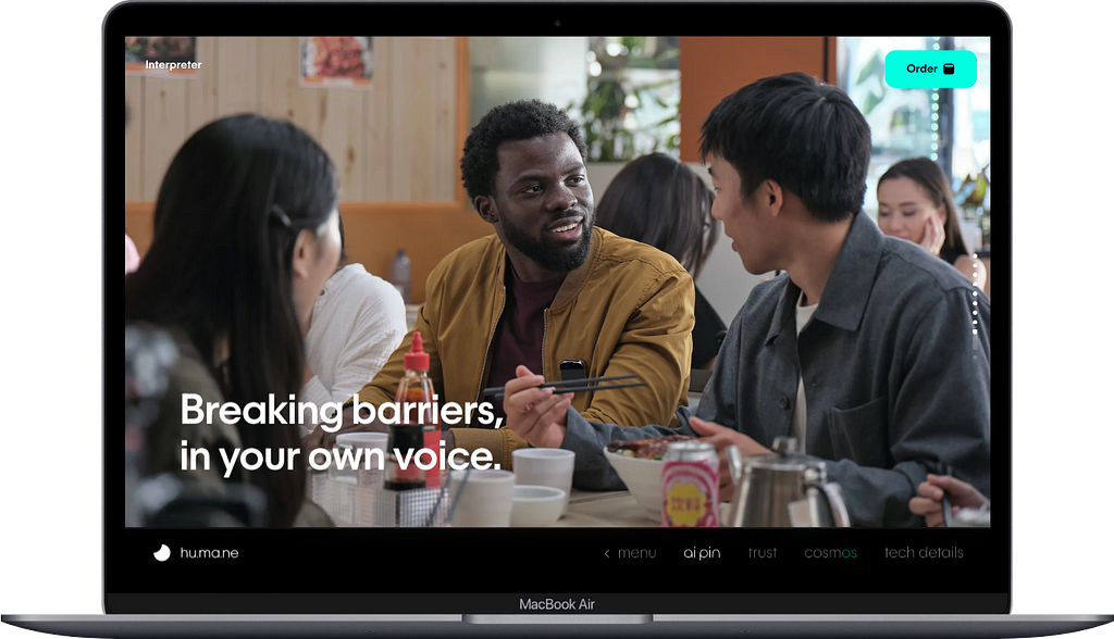 A laptop showing the landing page for Ai Pin by Humane in which people in a restaurant are talking to each other with the text “Breaking barriers, in your own voice” as the heading.