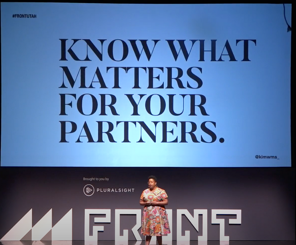 Kim Williams on stage with “know what matters for your partners” on the slide in the background