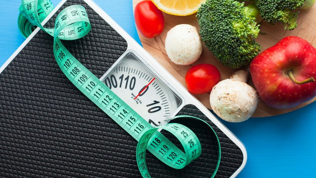 Weight scale, measurement tape and a lot of veggie together for a great idea to have weight control
