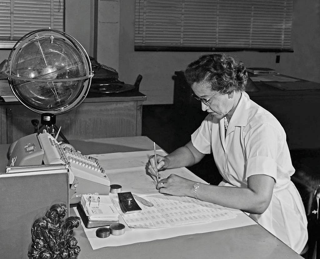 Katherine Johnson at work at NASA. She is sitting at a desk writing.