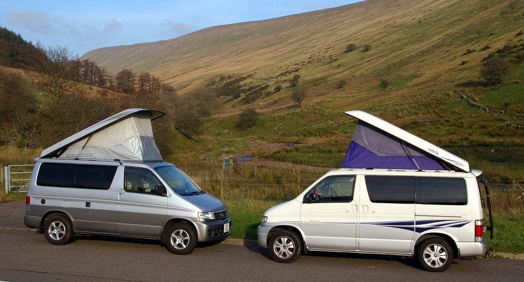 Two campervans parked in front of hills