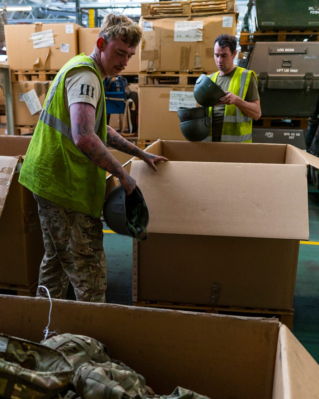 Soldiers packing helmets into large cardboard boxes
