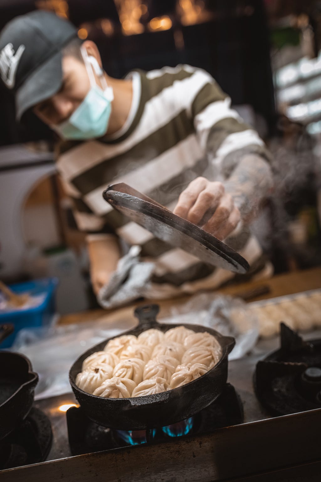 Taiwanese street vendor checking on the dumplings he is cooking