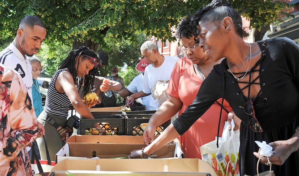 Community members fill bags of groceries in an assembly line outside