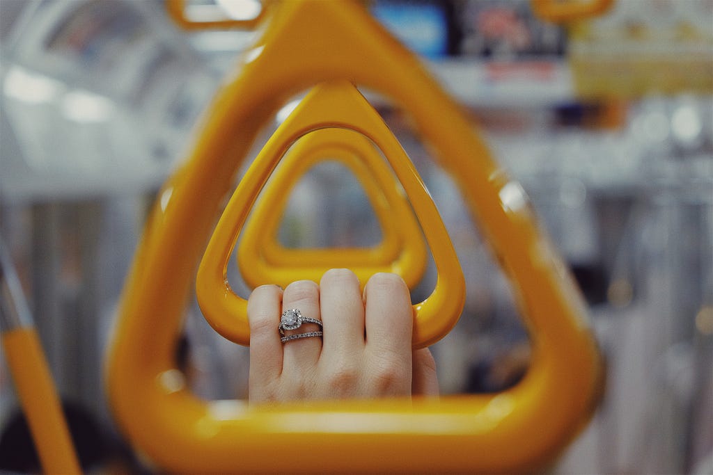 Image of a woman’s hand holding a yellow handle in a metro. Traffic jam hours in a big city.