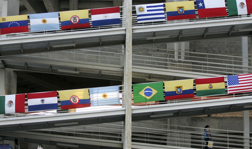 A woman walks on a ramp decorated with the flags of various countries of Latin America.