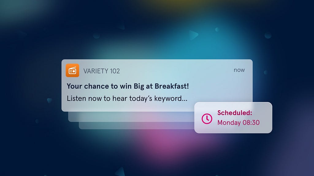 An illustration of an example push notification which reads “Variety 102. Your chance to win Big at Breakfast! Listen now to hear today’s keyword…”. Next to it is a bubble containing “Scheduled: Monday 08:30” with a clock icon.